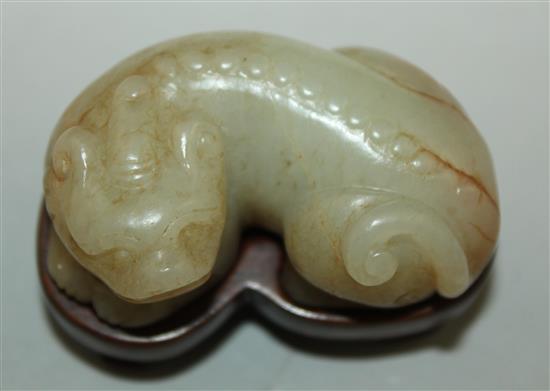 A Chinese pale celadon and russet jade recumbent figure of a bixi, 19th century, 5cm, wood stand